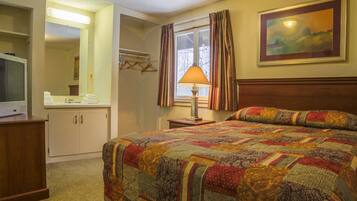 Cozy retreat with a neatly made bed, bedside table, and window with curtains, perfect for a restful stay.