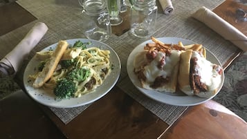Two plates of pasta and sandwiches on a table with a placemat.