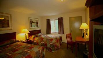 Quarto de hotel com duas camas, uma escrivaninha, uma cadeira e uma televisão.