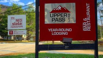 A sign for the Upper Pass Lodge, indicating it is a year-round lodging and bar/restaurant.
