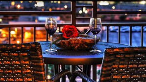 A table with two wine glasses and a red rose, overlooking a cityscape at night. - Tahiti Village Resort & Spa (Las Vegas)