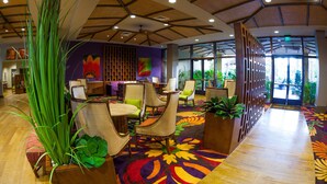 A lobby with wooden flooring, green plants, and a colorful carpet. There are chairs and a reception desk. - Tahiti Village Resort & Spa (Las Vegas)