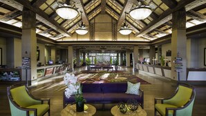 A spacious lobby with a high ceiling, wooden beams, and a central seating area with a sofa and two chairs. - Tahiti Village Resort & Spa (Las Vegas)