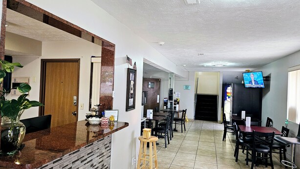 A hotel lobby with a reception desk, seating area, and a television mounted on the wall.