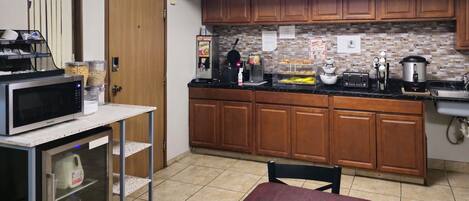 Una cocina compacta con armarios de madera, un microondas, una cafetera y un tostador.