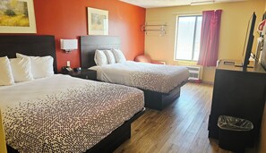 A hotel room with two beds, a desk, a chair, a TV, and a window with curtains.