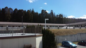 A building with a white fence, a parking area with cars, and a clear sky. - Budget Host Midway Inn (Bedford)