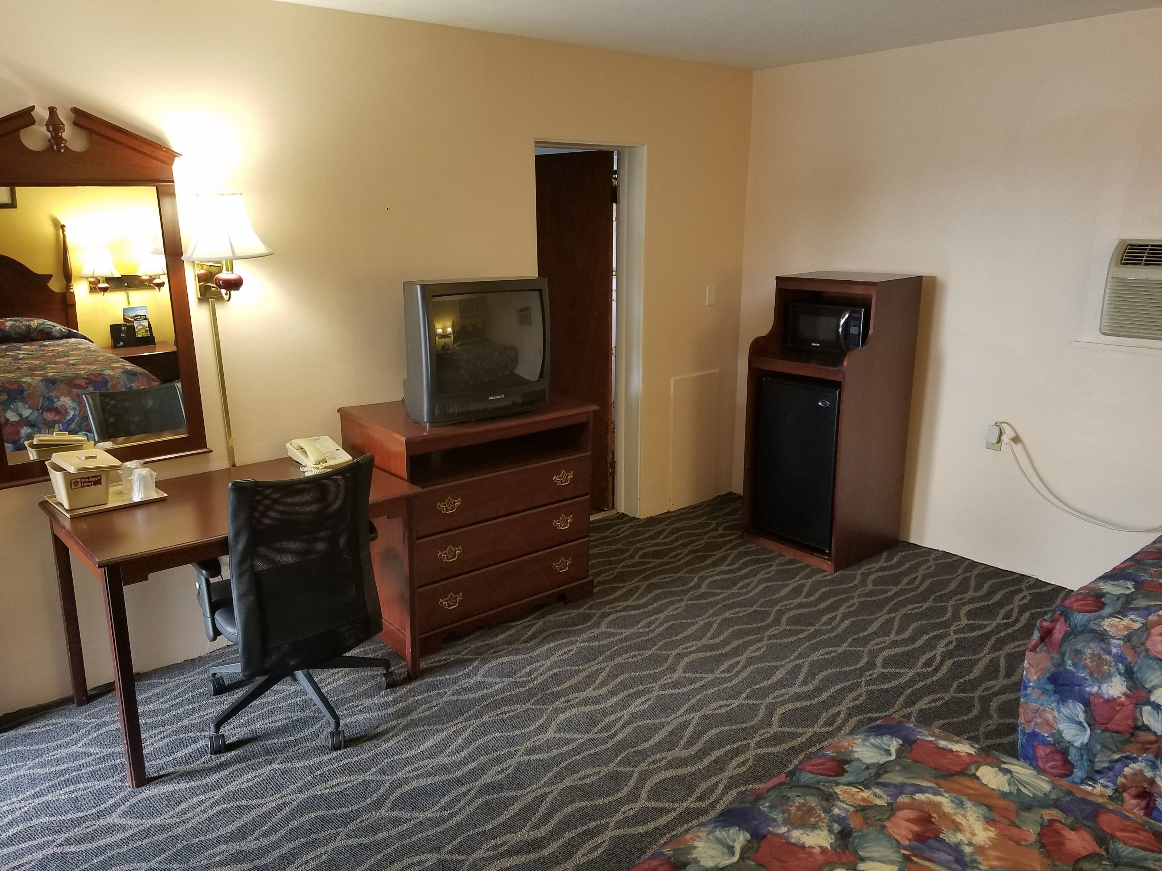 Habitación de hotel con cama, escritorio con teléfono, televisor, microondas y una silla.