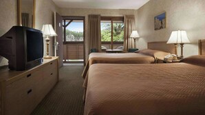 A hotel room with two beds, a TV, a desk, and a window with a view of trees. - Magnuson Grand Rushmore View (Keystone)