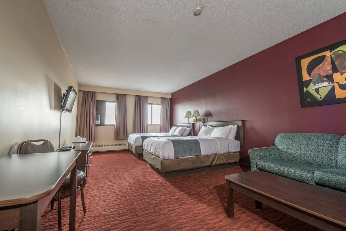 Una habitación de hotel con una cama, un sofá, un escritorio y un televisor.