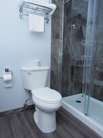 Un baño moderno con inodoro, cabina de ducha de vidrio y perchero para toallas.