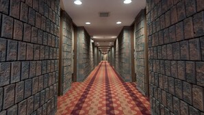 A long, narrow hallway with patterned carpet and brick walls. - Argyll Plaza Hotel (Edmonton)