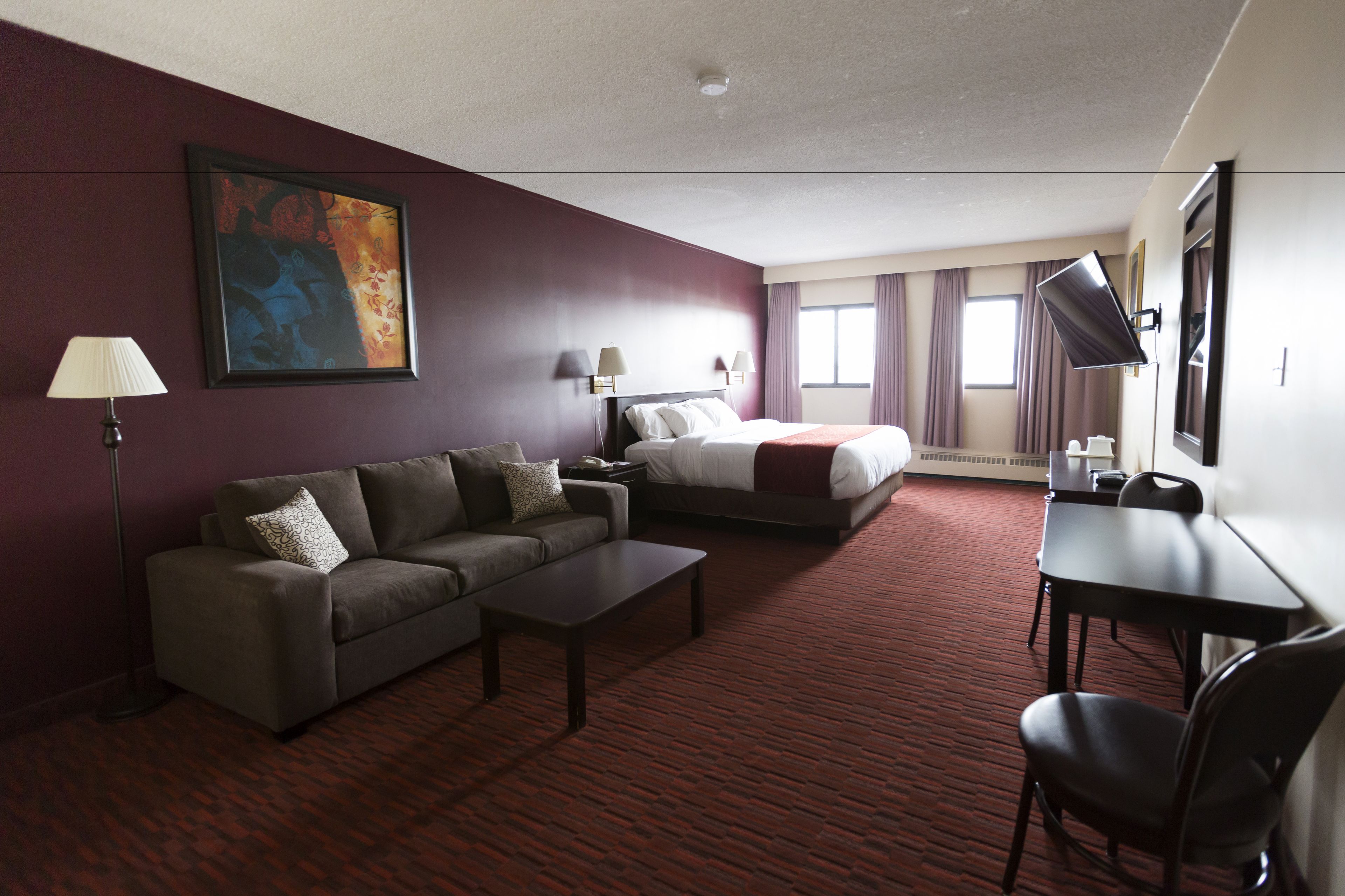 A hotel room with a sofa, a bed, a desk, and a TV.