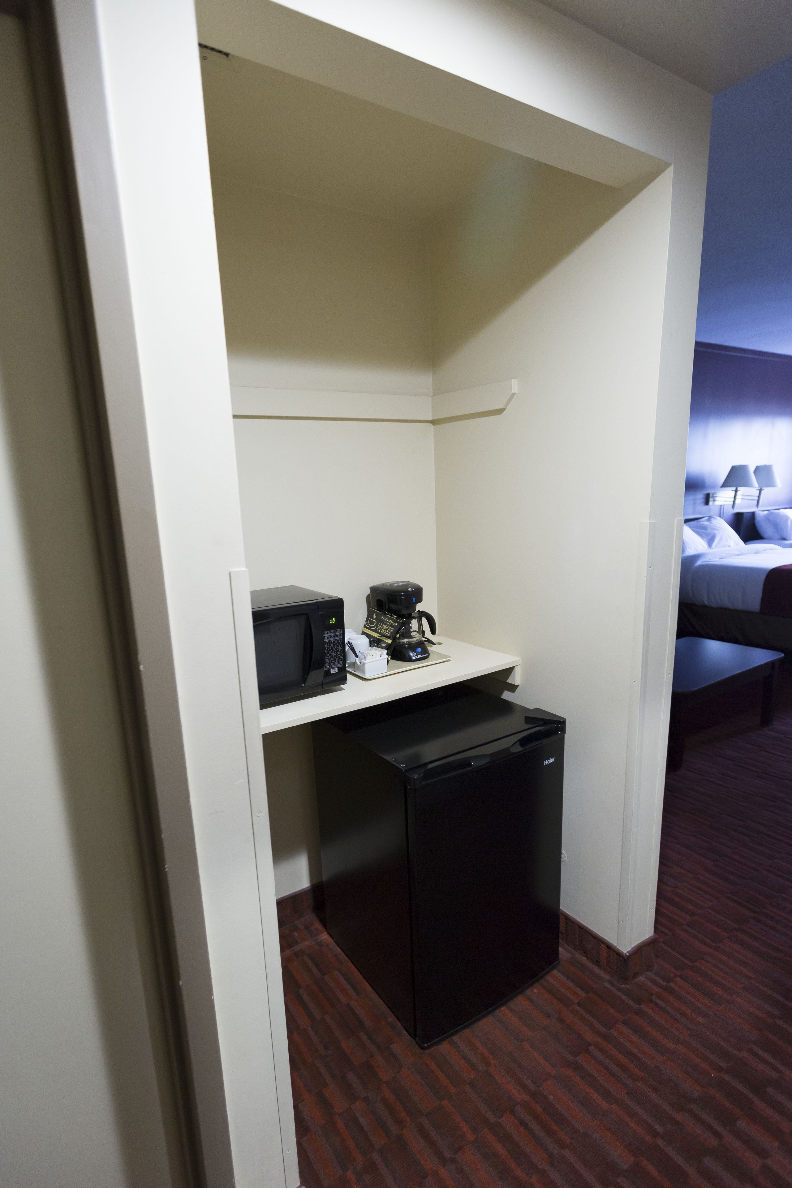 Habitación de hotel compacta con kitchenette que incluye microondas, cafetera y refrigerador.