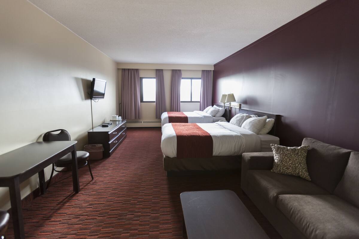 Una habitación de hotel con cama, escritorio, sillón, sofá y televisor.