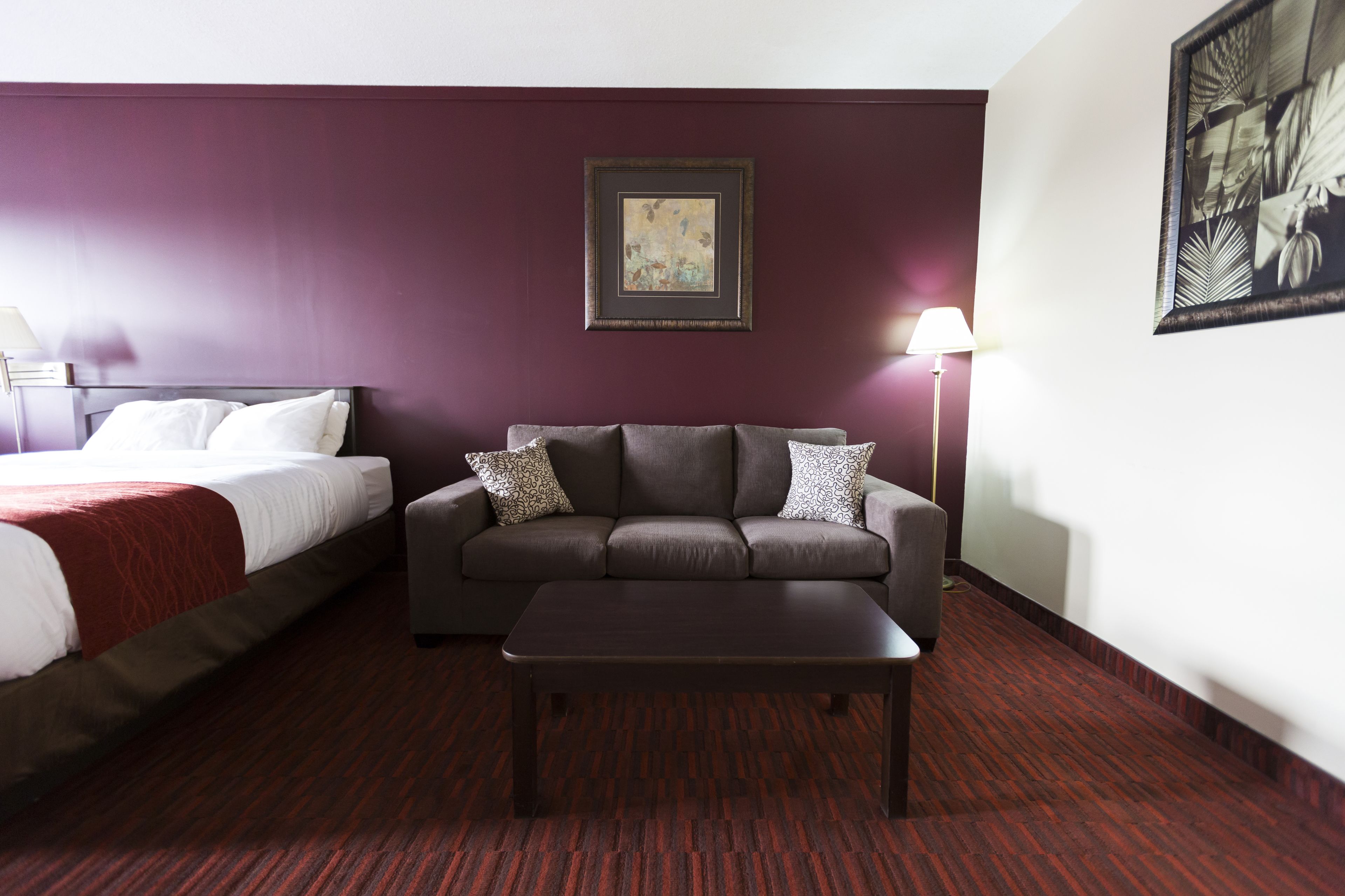 Hotellihuone, jossa on sänky, sohva ja sohvapöytä.