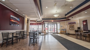 A spacious indoor area with multiple tables and chairs, a clear entrance, and a visible exit. - Argyll Plaza Hotel (Edmonton)