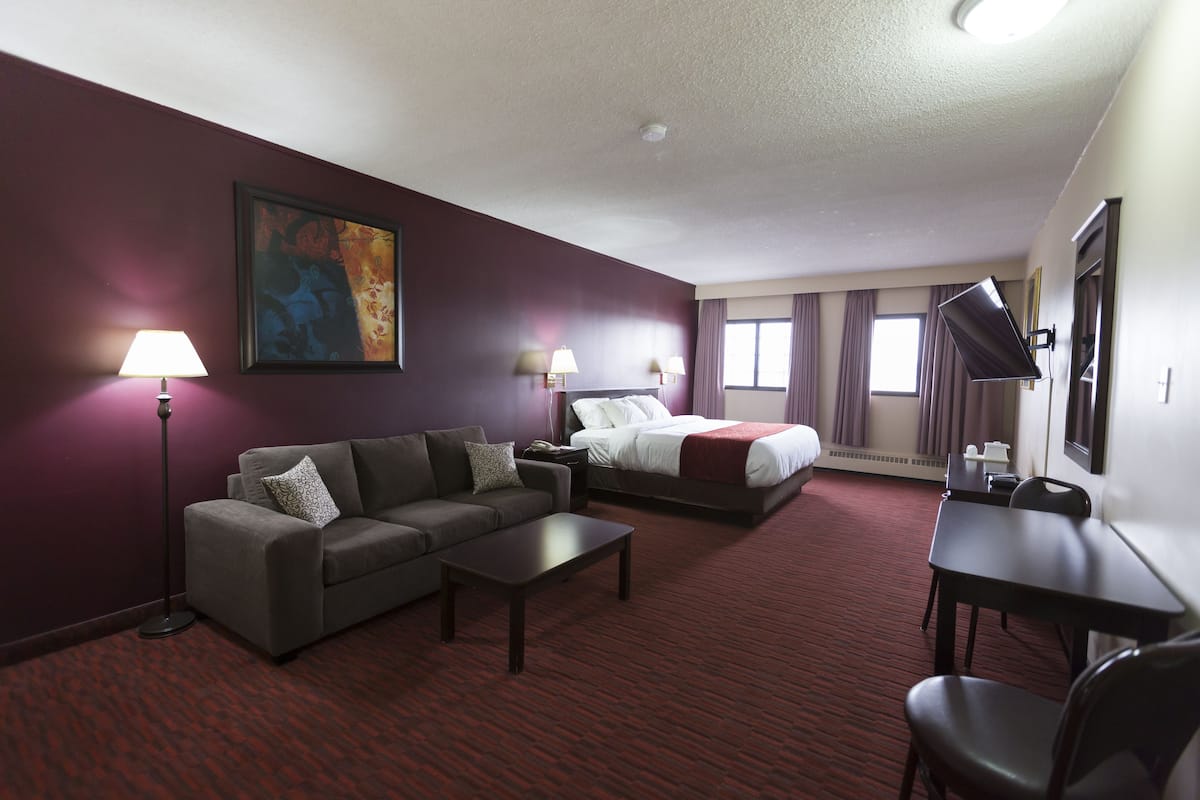 Una habitación de hotel con sofá, cama, escritorio y lámpara.
