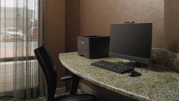 A small office space with a desktop computer, keyboard, and mouse on a granite countertop.
