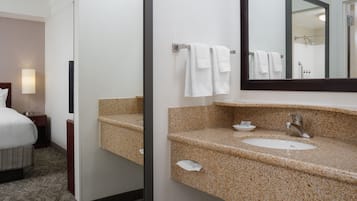 A hotel bathroom with a bed, a sink, and a large mirror.