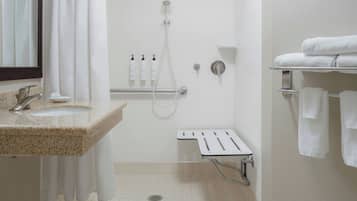 Un baño con lavamanos, ducha, barra de apoyo y toallero.