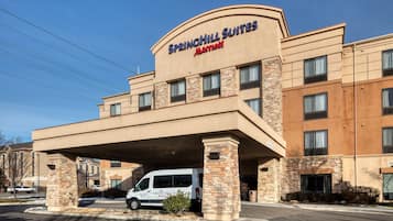 Un hotel SpringHill Suites Marriott con entrada cubierta y una camioneta blanca estacionada al frente.