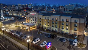 A hotel with a parking lot, a road with a pedestrian crossing, and a mountain in the background.