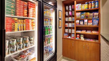 Una sección refrigerada con diversos alimentos y bebidas, y un mueble de madera con aperitivos y otros productos alimenticios.