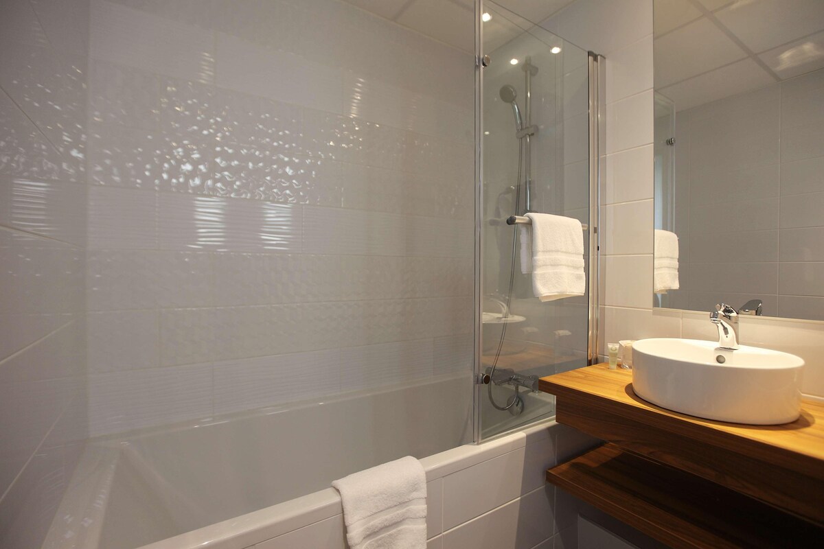 A modern bathroom with a glass-enclosed shower, a white sink, and a wooden vanity.