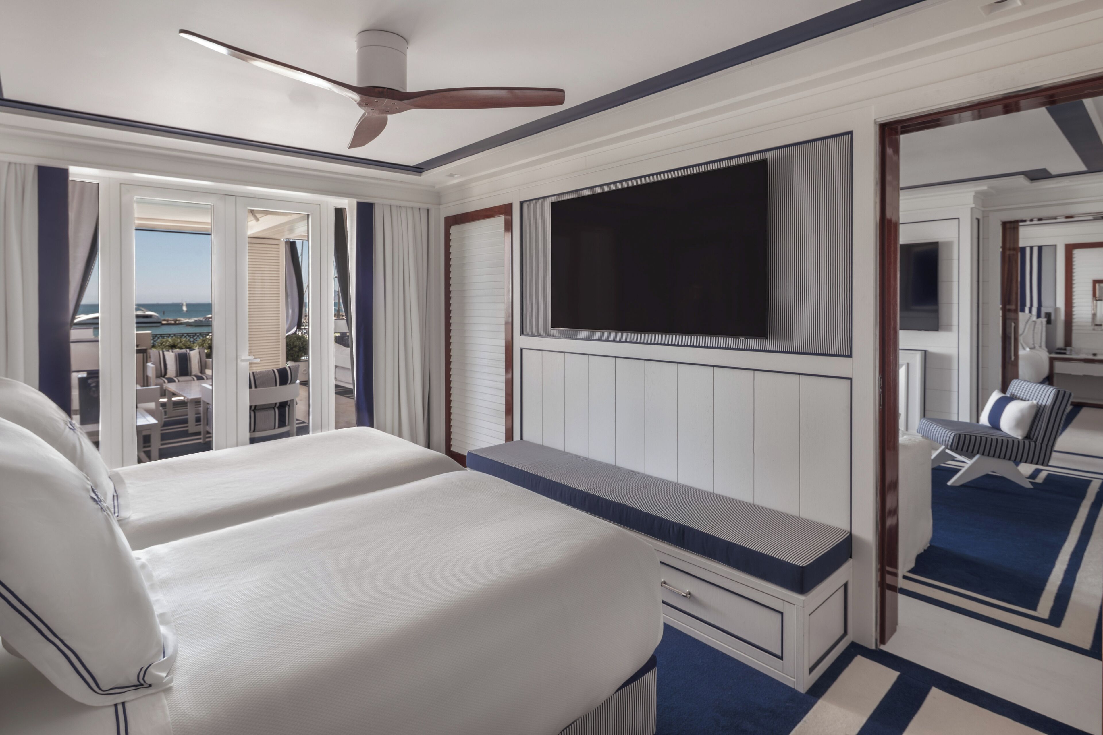 A hotel room with a bed, a desk, a TV, and a view of the ocean.