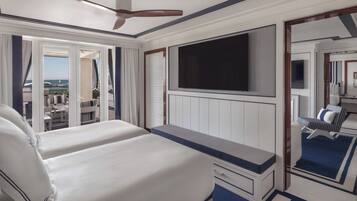 A hotel room with a bed, a desk, a TV, and a view of the ocean.
