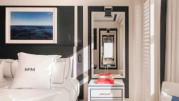A hotel room with a bed, a nightstand, a mirror, and a framed picture of the ocean.