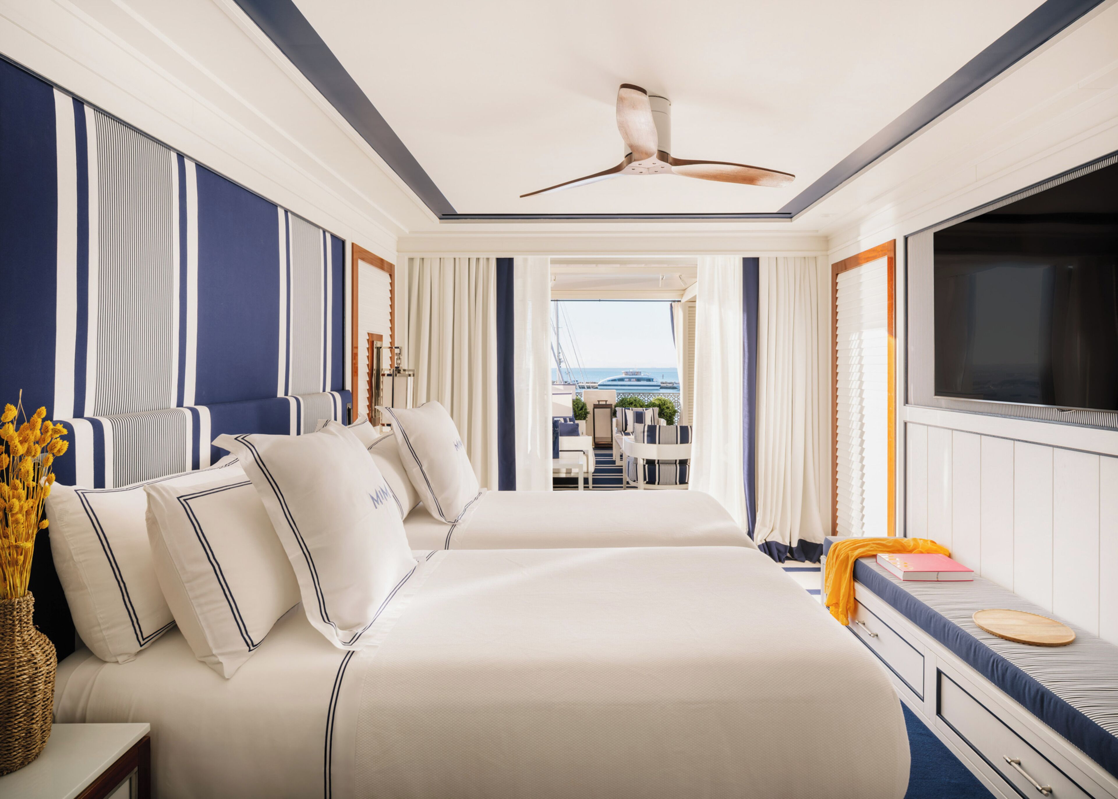 A hotel room with a large bed, a desk, and a view of the sea.