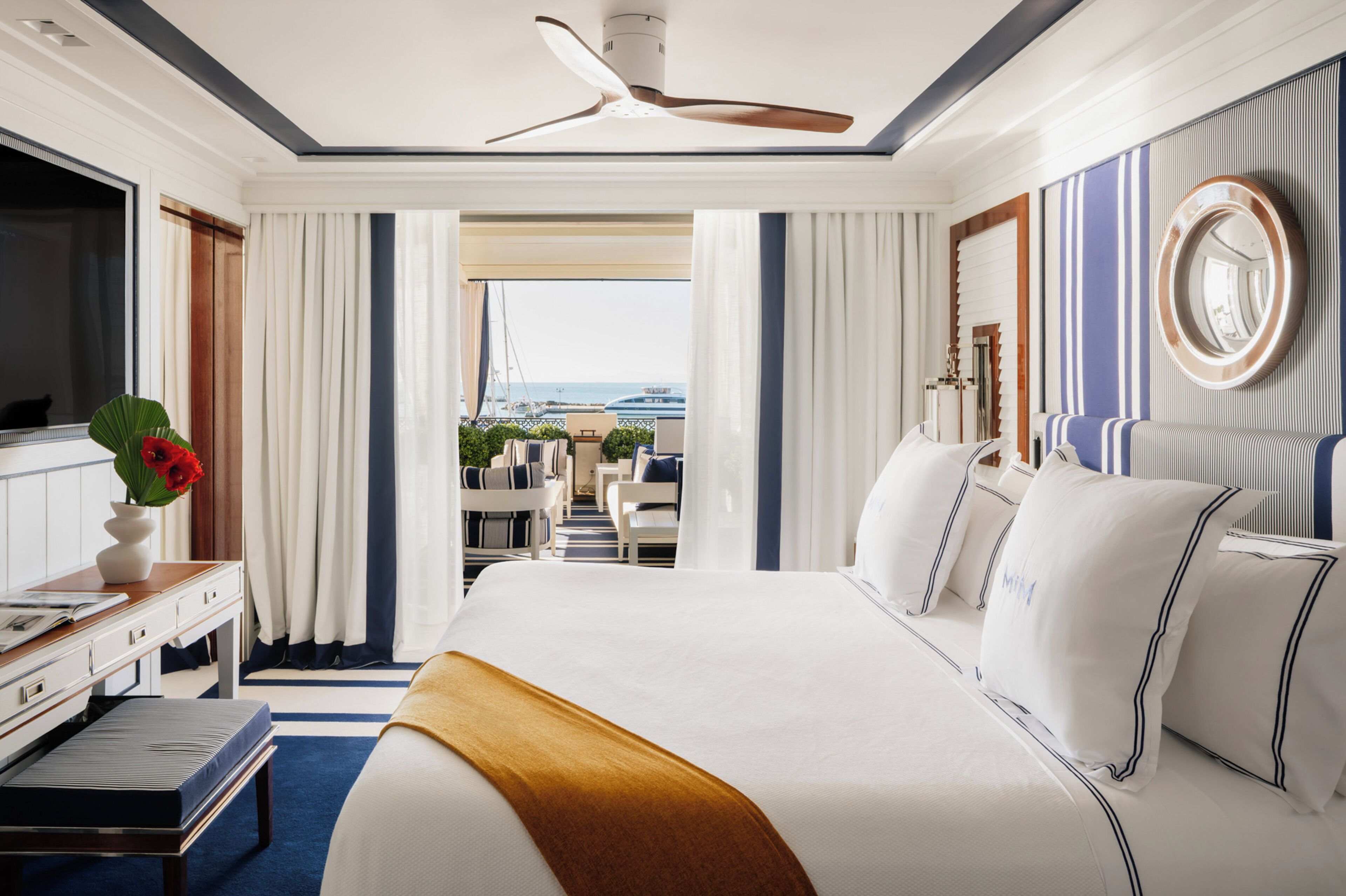 Habitación de hotel con una cama grande, un escritorio con computadora, televisión y vista al océano.