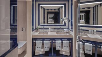 Un baño moderno con lavamanos dobles, un espejo grande y varias toallas con la marca 'MiM'.