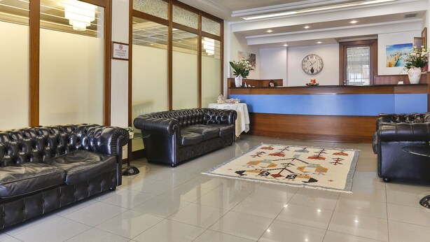 Un hall de hotel con sofás de cuero, una recepción y una alfombra decorativa.