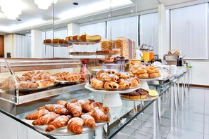 A buffet with various baked goods including pastries and muffins. - Sunset (Rimini)