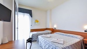 Ett hotellrum med två sängar, ett skrivbord, en stol, en TV och en tavla på väggen.