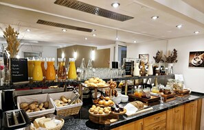 Ein Buffet mit verschiedenen Speisen und Getränken, darunter Brot, Gebäck und eine Auswahl an Säften.