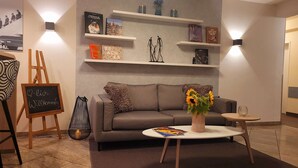 Un salon moderne avec un canapé gris, une table basse et une bibliothèque.