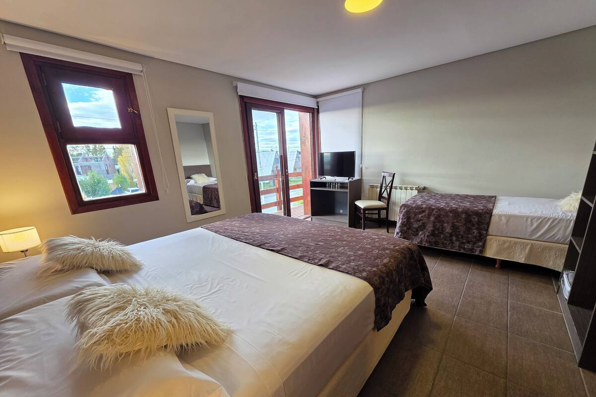 Une chambre d’hôtel avec deux lits, un bureau, une chaise et un téléviseur.