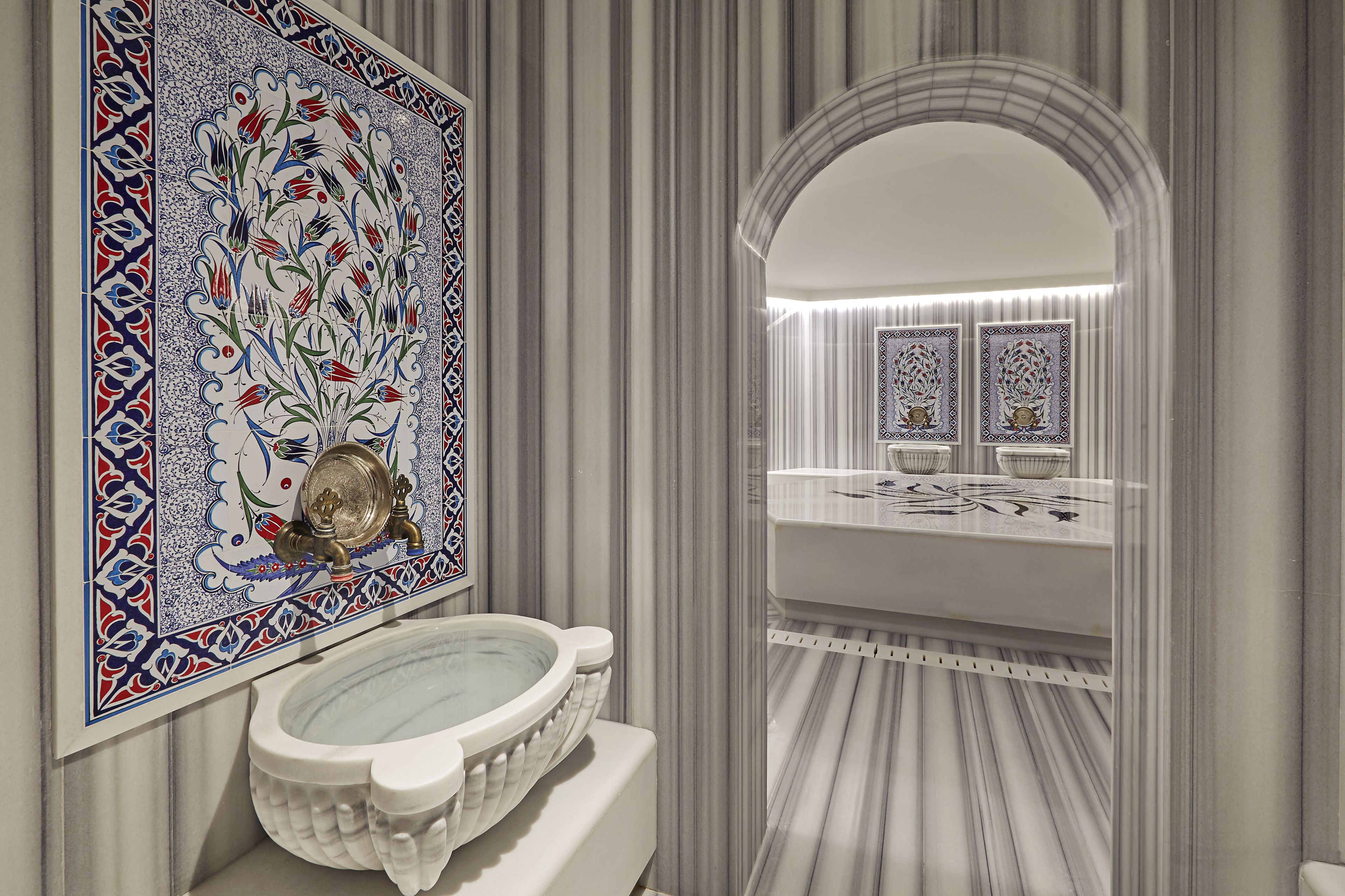 Ein Badezimmer mit einem großen Spiegel, einem Waschbecken mit dekorativer Schüssel und einer Wand mit vertikalen Streifen.