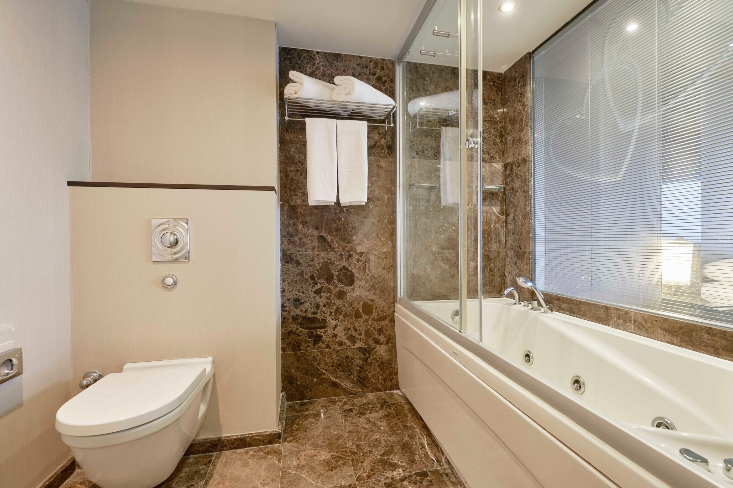A modern bathroom with a toilet, a glass-enclosed shower, and a large bathtub.