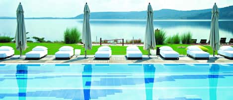 Una piscina al aire libre, sombrillas, sillones reclinables de piscina