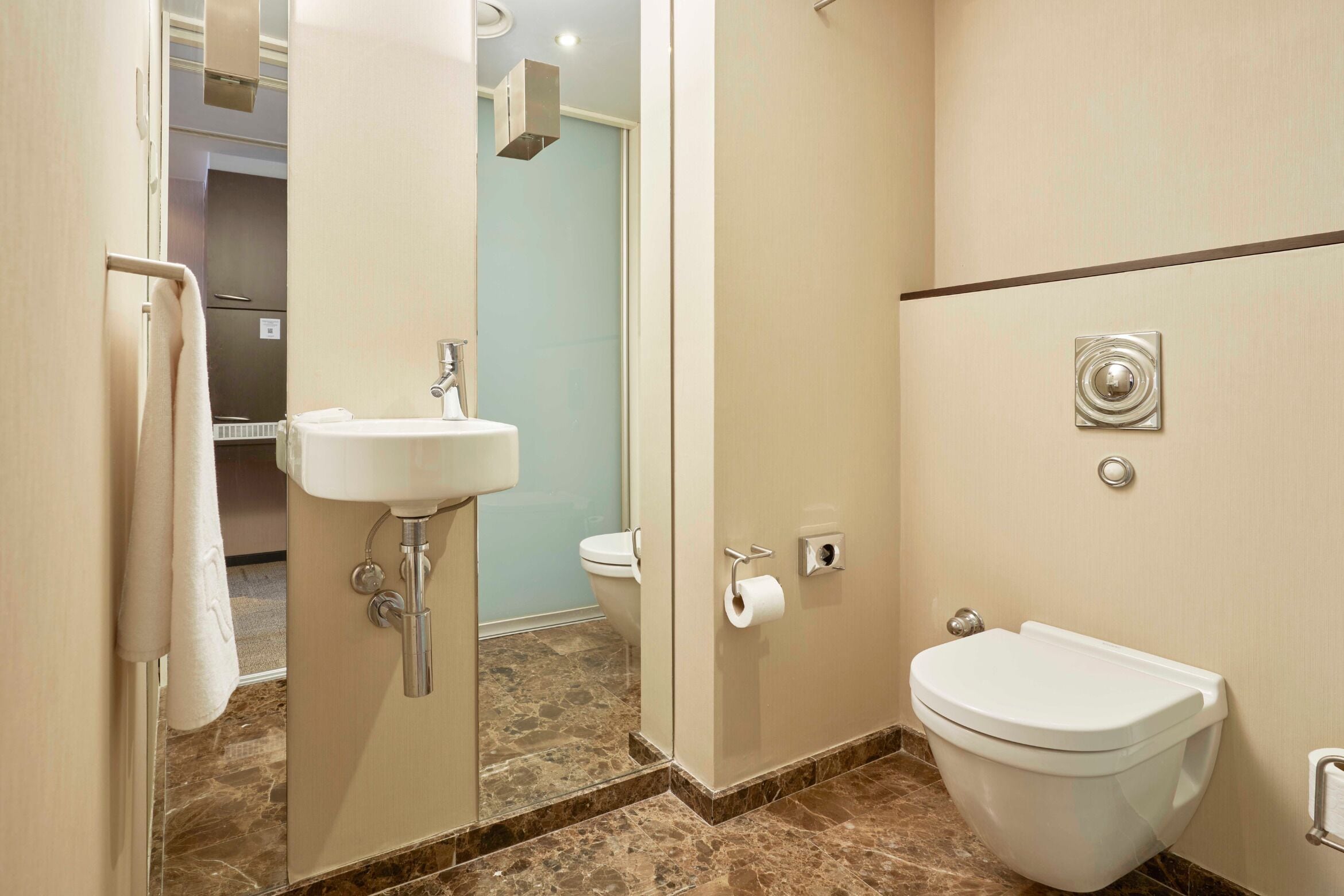 Un baño con lavamanos, inodoro y espejo.