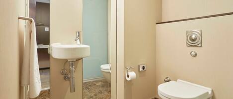 Un baño con lavamanos, inodoro y espejo.