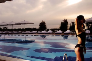 Una piscina al aire libre, sombrillas, sillones reclinables de piscina