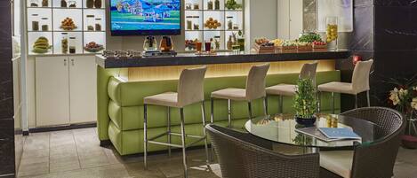 A bar area with a television, shelves of snacks, and a green counter.