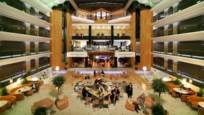 A spacious lobby with multiple seating areas, a central bar, and a high ceiling with geometric lighting. - Richmond Nua Wellness -Spa - Adults Only (Sapanca)