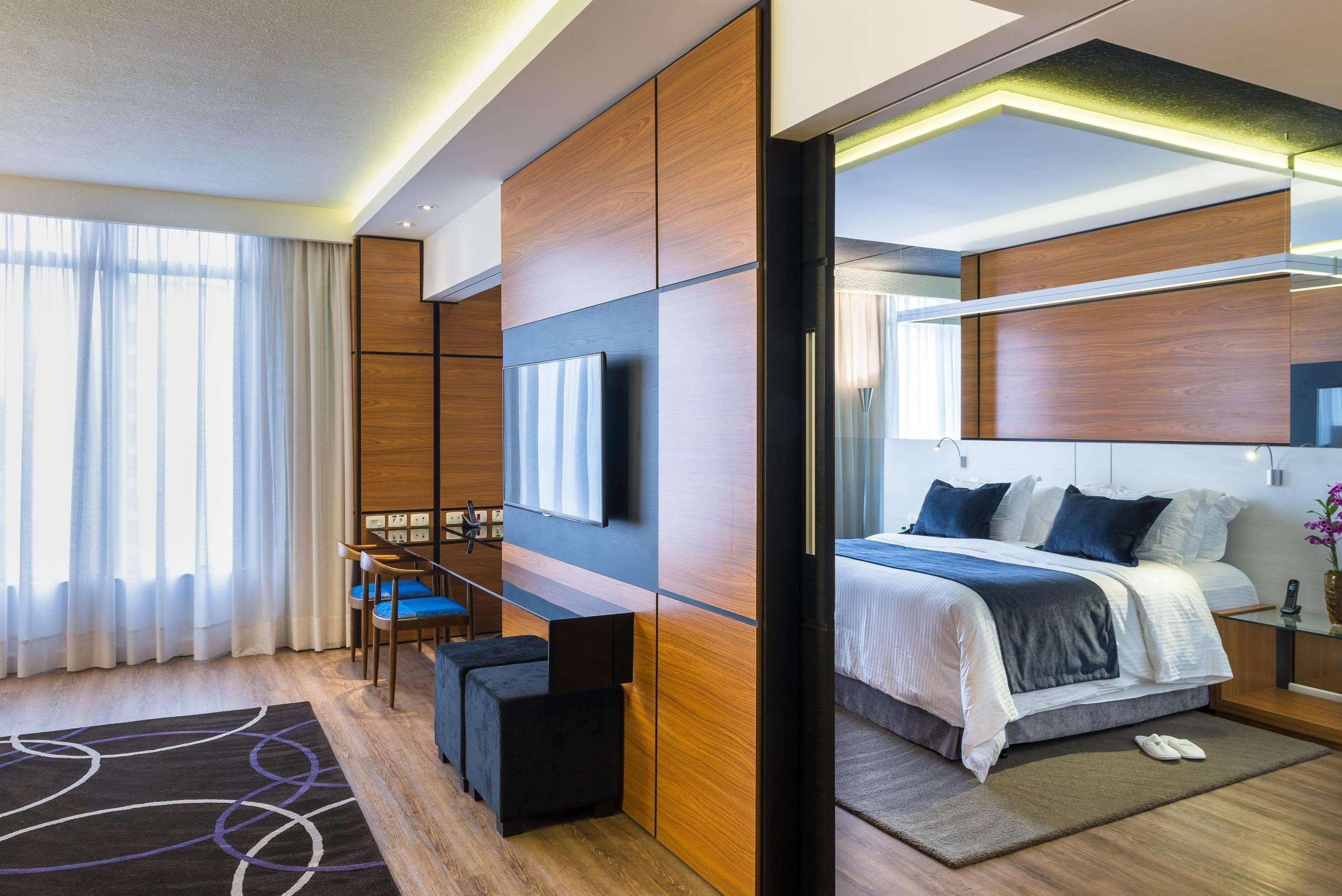 A modern hotel room with a bed, desk, and seating area.
